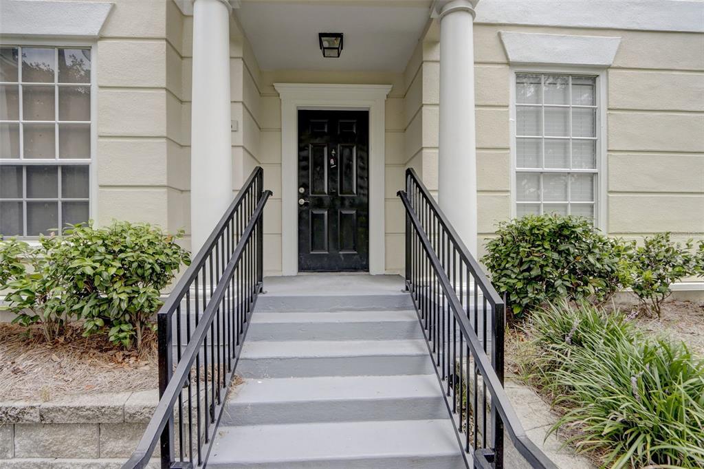 A black front door is centered between two white columns at the top of concrete stairs — 236 CELEBRATION BOULEVARD UNIT 236, CELEBRATION, FL