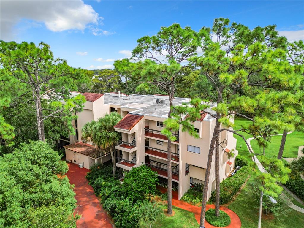 An aerial view of a multi-story apartment building surrounded by trees and a paved path — 1158 CARMEL CIRCLE UNIT 430, CASSELBERRY, FL