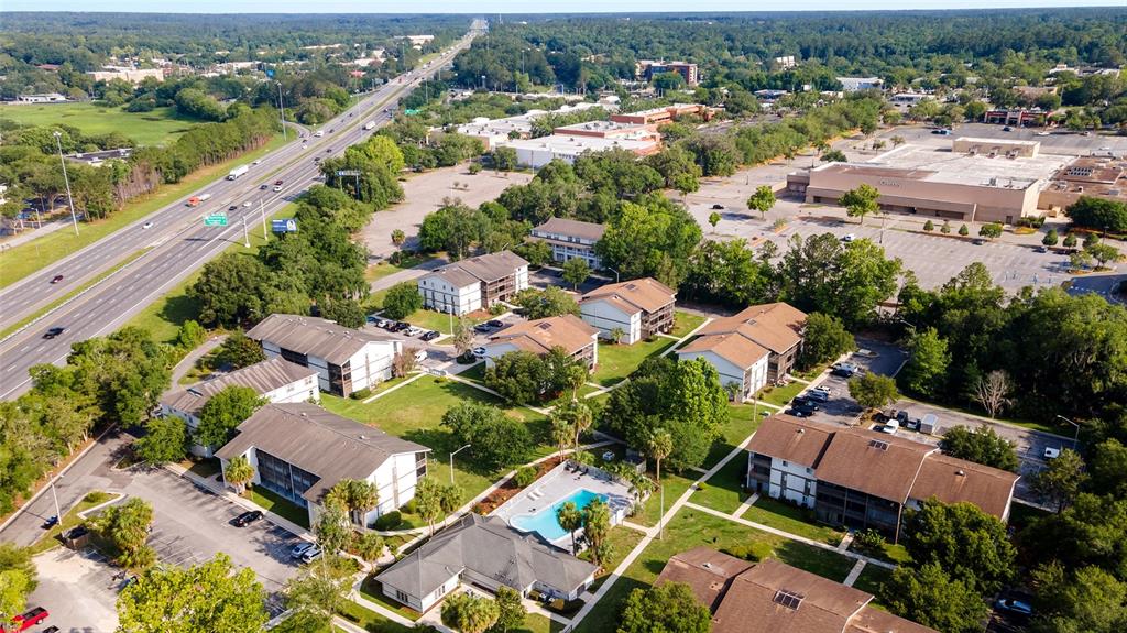 An aerial view shows a multi-building apartment complex with a pool and adjacent highway — 6519 W NEWBERRY ROAD UNIT 1210, GAINESVILLE, FL
