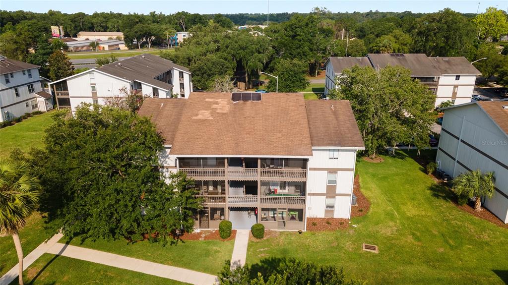 An aerial view shows a multi-story apartment building with a brown shingled roof and balconies — 6519 W NEWBERRY ROAD UNIT 1210, GAINESVILLE, FL