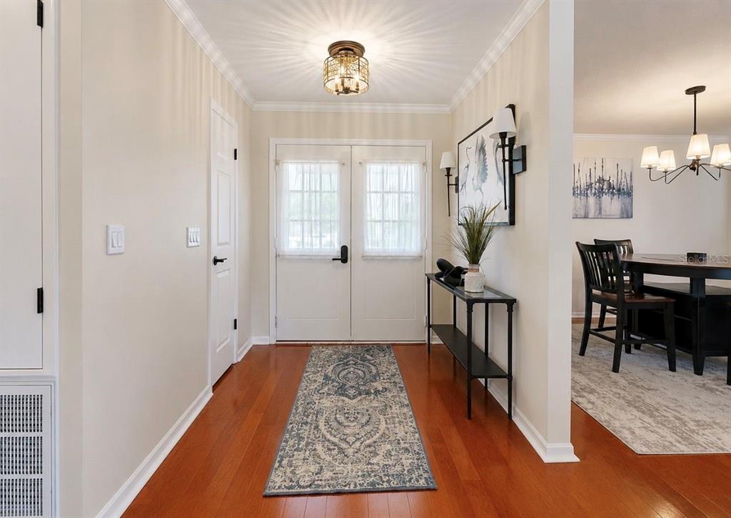 A bright entryway features hardwood floors, a patterned runner rug, and a glass-topped console table — 1005 HIGHGROVE COURT, VALRICO, FL