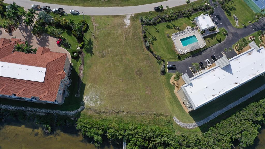 An aerial view shows a vacant grassy lot situated between two large multi-story residential buildings — 99 N MARION COURT, PUNTA GORDA, FL