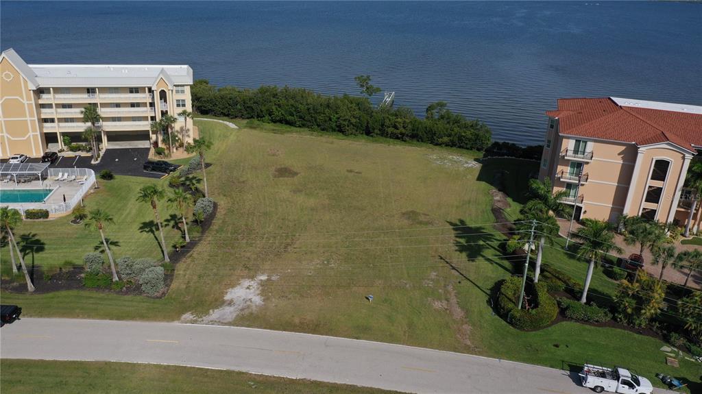An aerial view shows a vacant grassy lot situated between two multi-story residential buildings — 99 N MARION COURT, PUNTA GORDA, FL