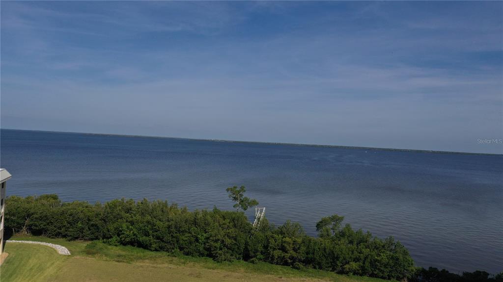 An elevated view shows a grassy shoreline with trees and a dock along a bay — 99 N MARION COURT, PUNTA GORDA, FL