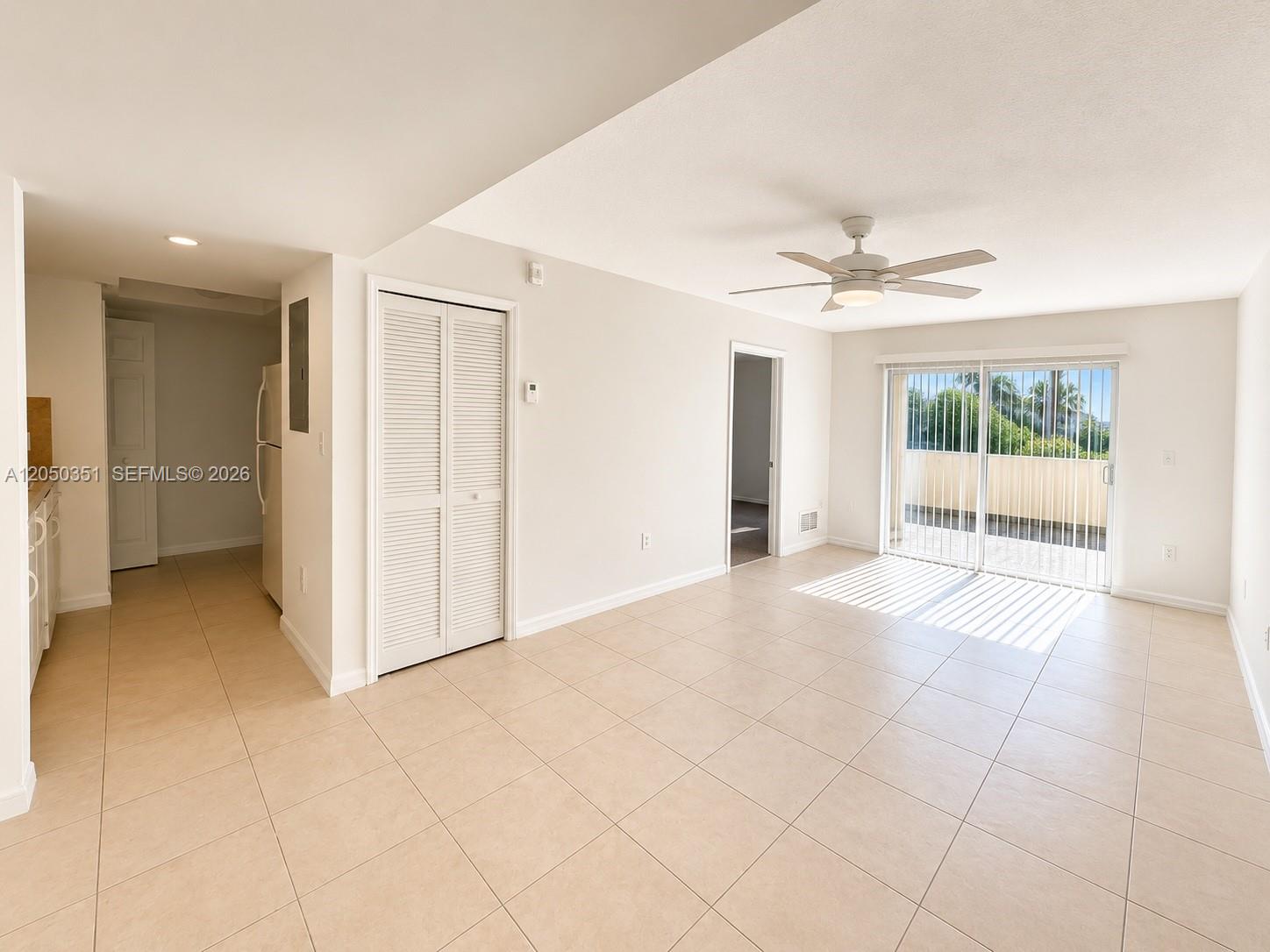 A bright living area features beige tile flooring, a ceiling fan, and sliding glass doors — 2415 NW 16th St Rd # 1, Miami FL 33125, MIAMI, FL