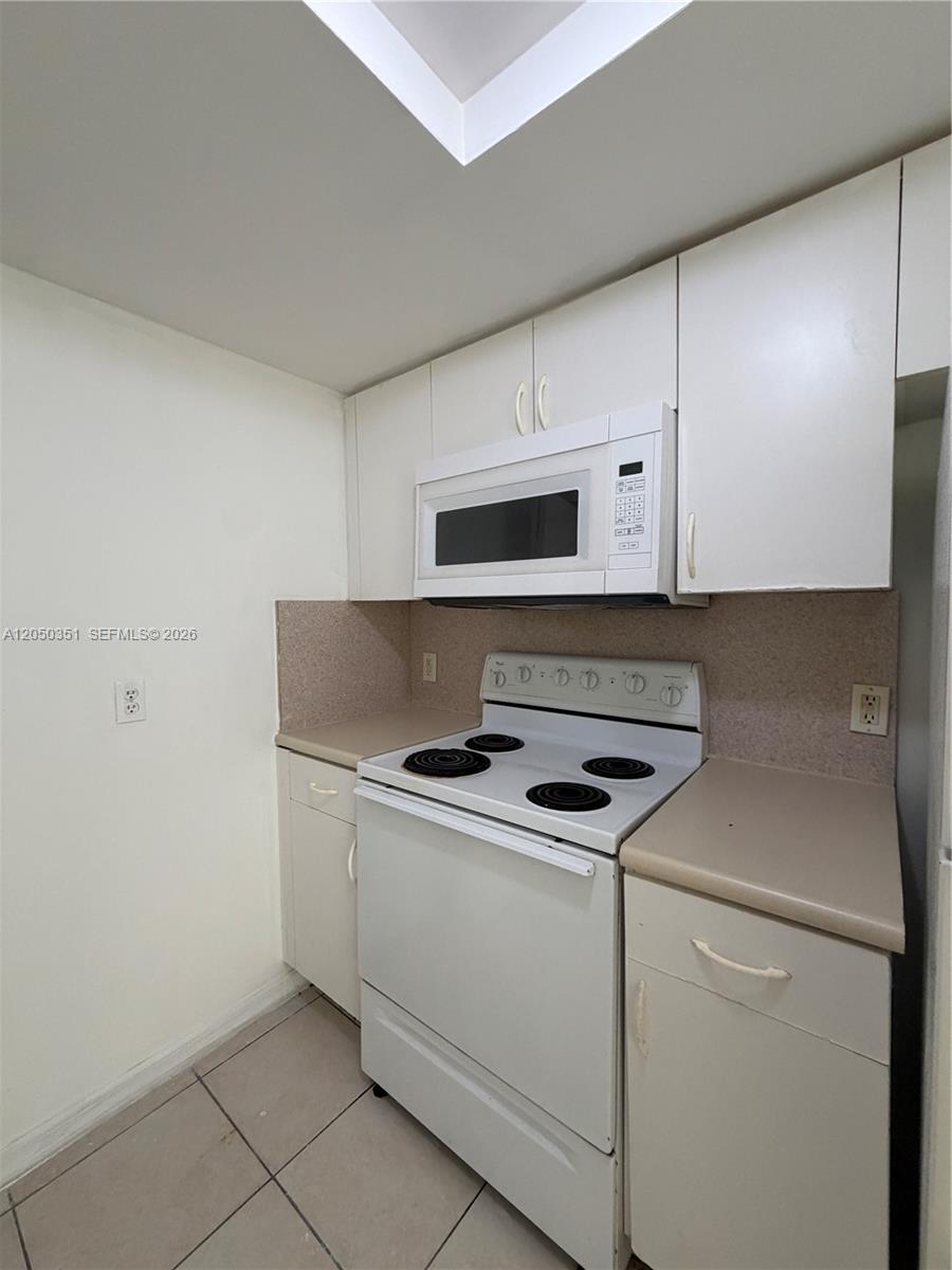 A kitchen features white cabinets, a white electric stove, and a mounted microwave — 2415 NW 16th St Rd # 1, Miami FL 33125, MIAMI, FL