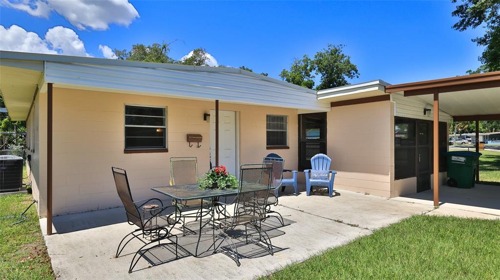 A concrete patio with a metal dining set sits outside a light-colored block house — 536 DOROTHY AVENUE, DAYTONA BEACH, FL