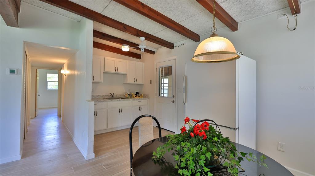 A kitchen and dining area features white cabinets, wood ceiling beams, and tile flooring — 536 DOROTHY AVENUE, DAYTONA BEACH, FL
