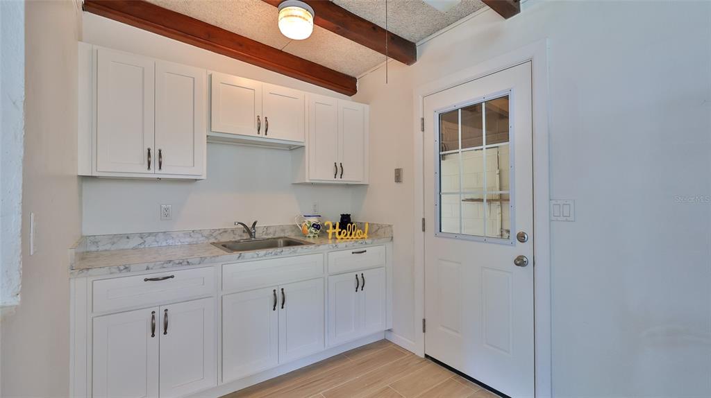 A small kitchen area features white cabinets, a marble-look countertop, and a glass-paneled door — 536 DOROTHY AVENUE, DAYTONA BEACH, FL