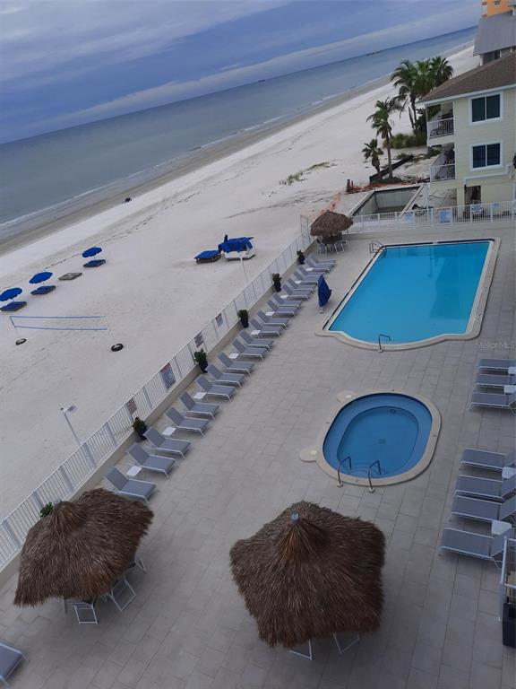 An elevated view shows a beachside pool area with lounge chairs and thatched umbrellas — 18500 GULF BOULEVARD UNIT 404, INDIAN SHORES, FL