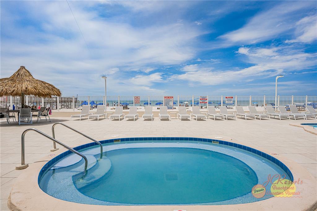 A circular hot tub sits on a paved pool deck overlooking the ocean — 18500 GULF BOULEVARD UNIT 404, INDIAN SHORES, FL