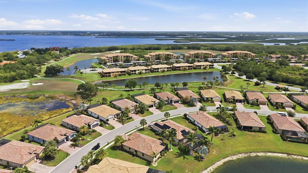 An aerial view shows a residential neighborhood with houses, apartment buildings, and a lake — 6540 WILLOWSHIRE WAY, BRADENTON, FL