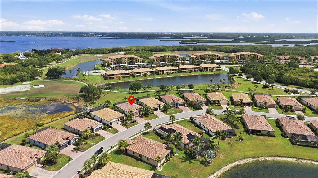 An aerial view shows a residential neighborhood with single-family homes, a lake, and apartment buildings — 6540 WILLOWSHIRE WAY, BRADENTON, FL