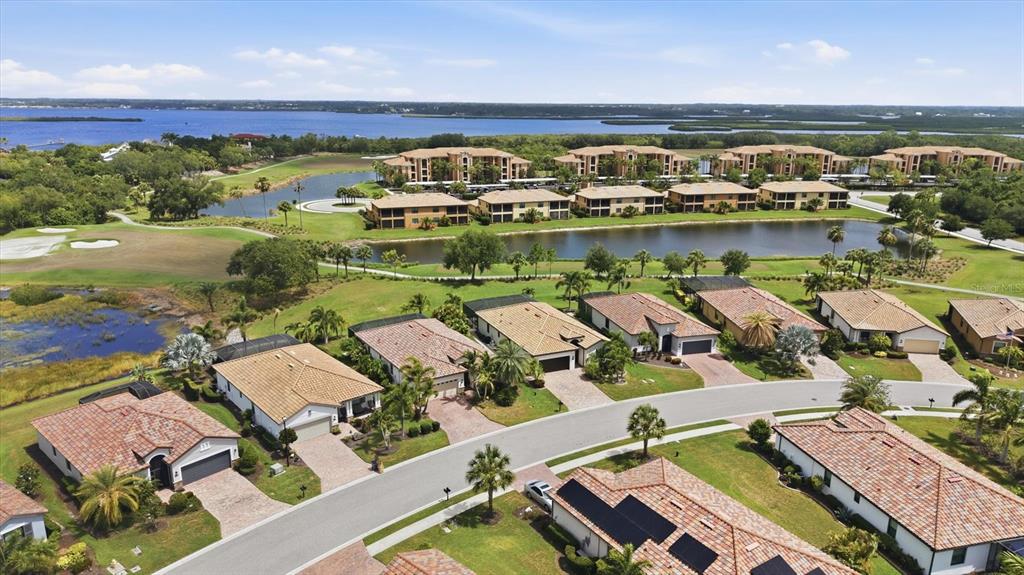 An aerial view shows a suburban neighborhood with single-family homes, apartment buildings, and a lake — 6540 WILLOWSHIRE WAY, BRADENTON, FL