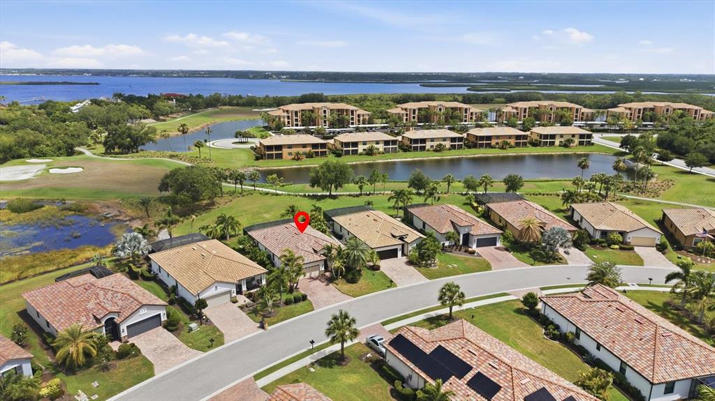 An aerial view shows a suburban neighborhood with single-family homes, a pond, and apartment buildings — 6540 WILLOWSHIRE WAY, BRADENTON, FL