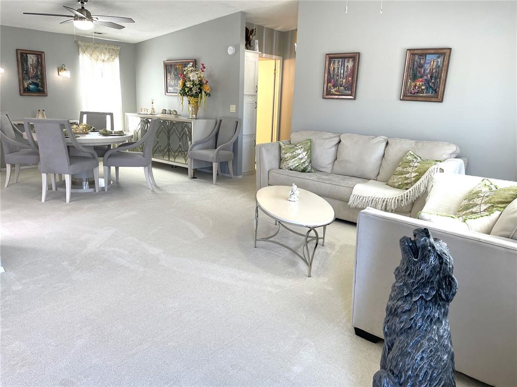 A living and dining area features light gray walls, carpeted floors, and neutral-toned furniture — 24437 HARBORVIEW ROAD UNIT 70, PORT CHARLOTTE, FL