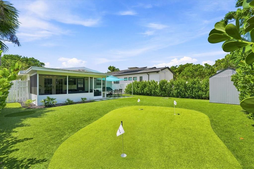A backyard features a putting green with three holes and a screened-in patio area — 2449 WOOD STREET, SARASOTA, FL