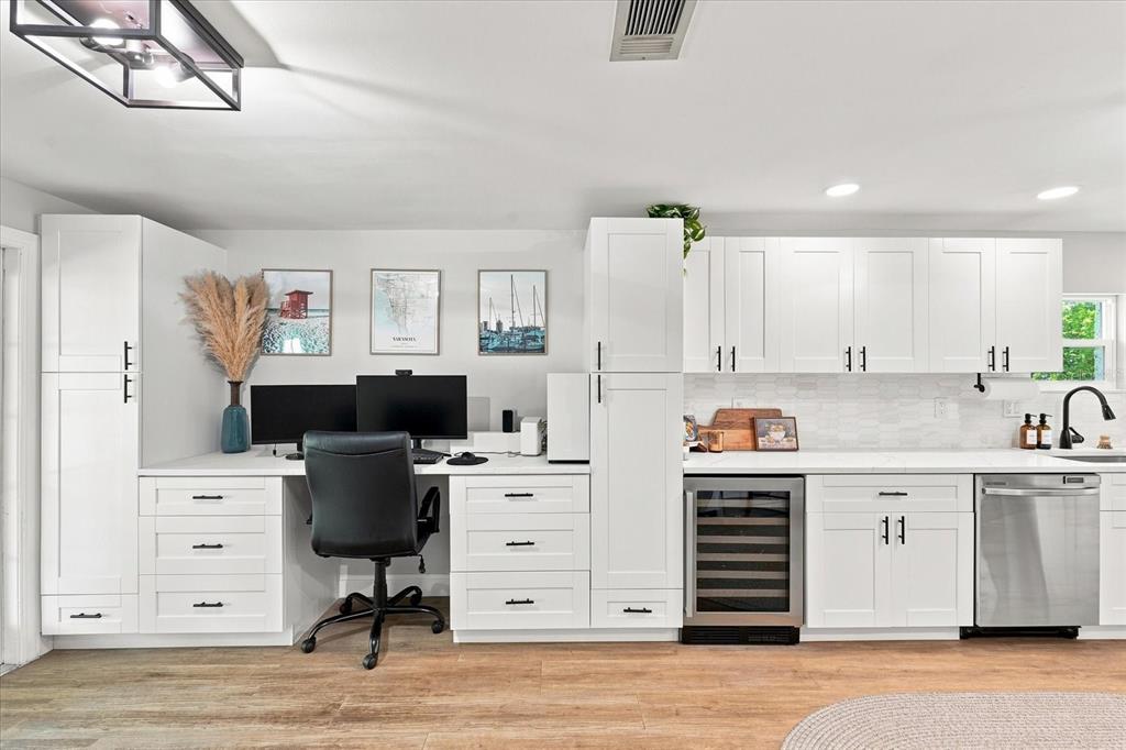 A white kitchen features a built-in desk area, cabinetry, a wine cooler, and stainless appliances — 2449 WOOD STREET, SARASOTA, FL