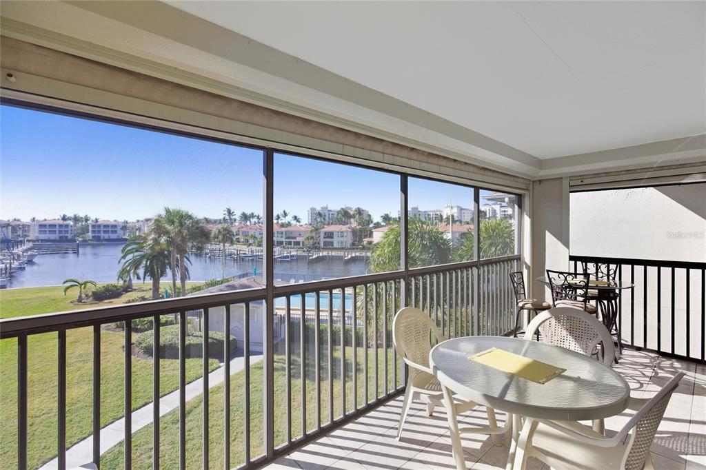 A screened-in balcony features patio furniture overlooking a marina and residential buildings — 3255 SUGARLOAF KEY ROAD UNIT 31C, PUNTA GORDA, FL