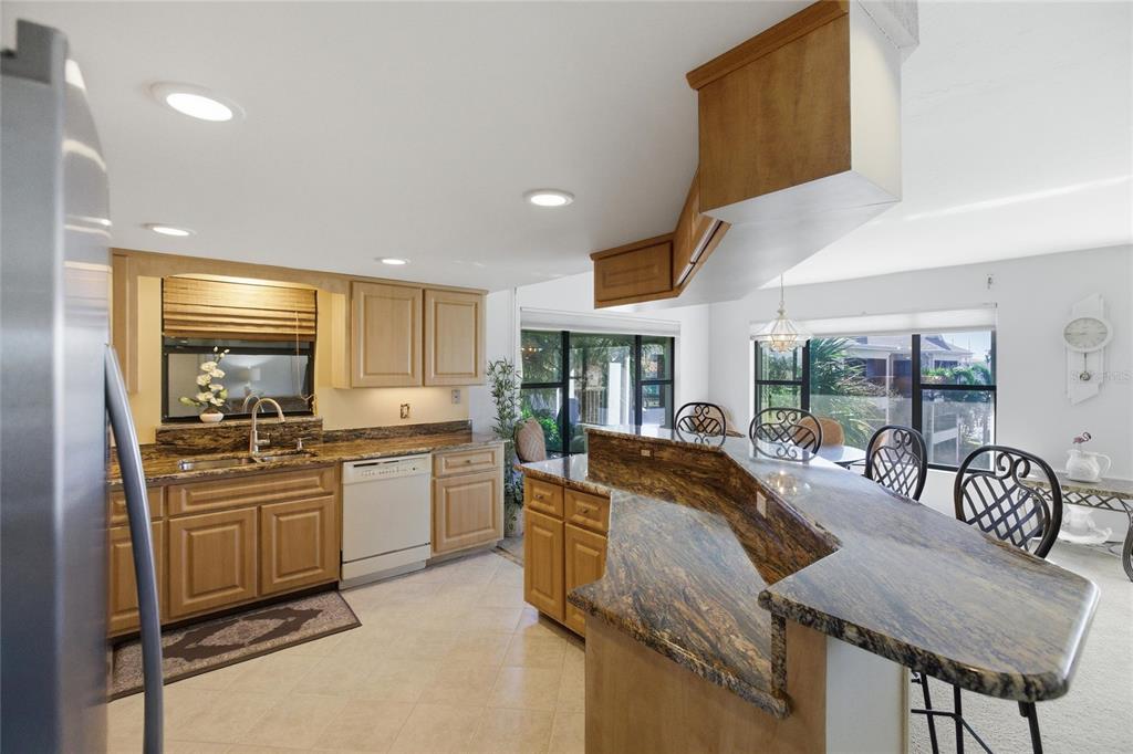 A kitchen features light wood cabinets, granite countertops, a breakfast bar, and tile flooring — 3255 SUGARLOAF KEY ROAD UNIT 31C, PUNTA GORDA, FL
