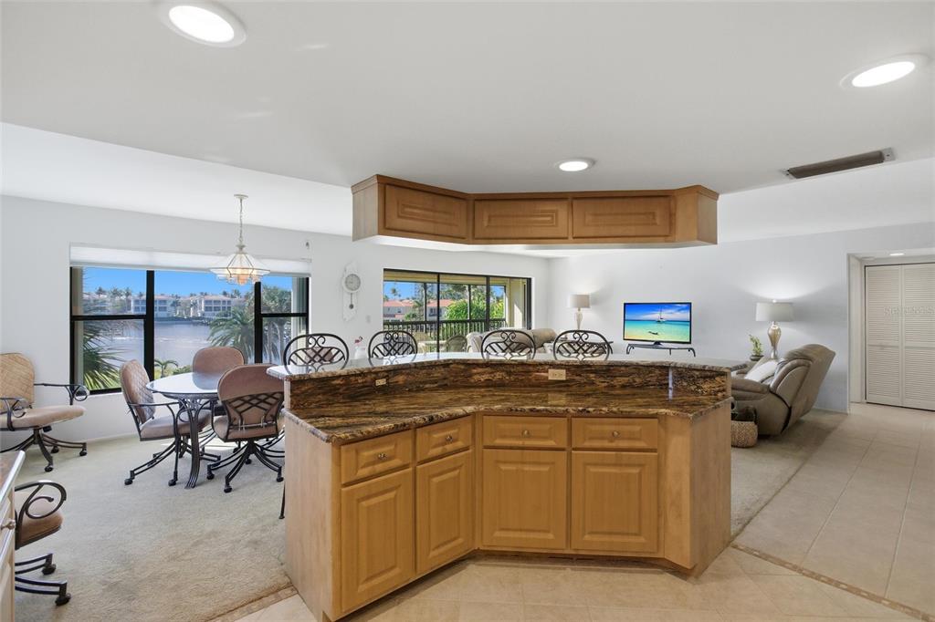 A kitchen island with granite countertops overlooks a dining area and living room with water views — 3255 SUGARLOAF KEY ROAD UNIT 31C, PUNTA GORDA, FL