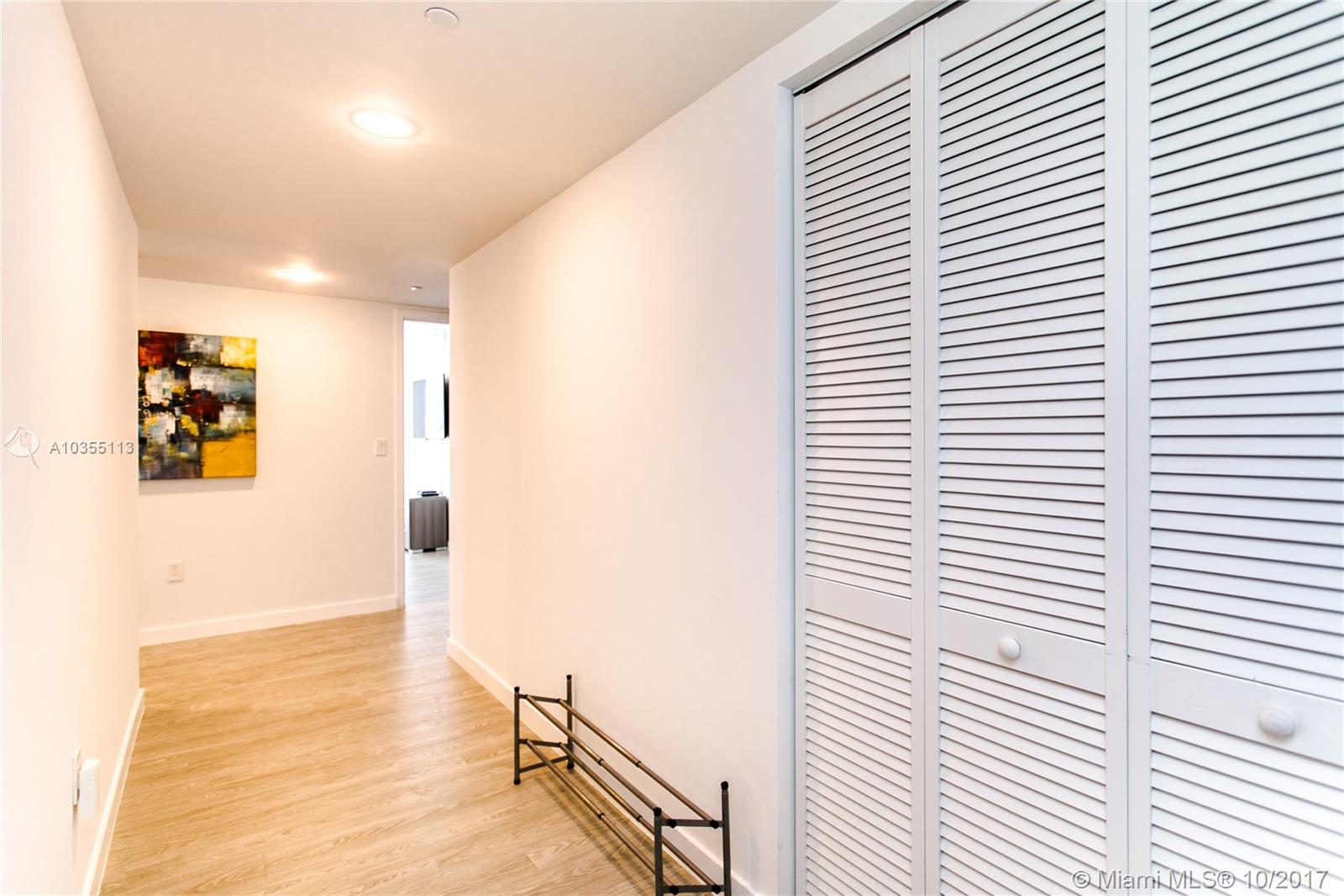 A hallway features light wood-look flooring, white walls, a louvered closet, and recessed lighting — 2600 E Hallandale Beach Blvd, Hallandale Beach FL 33009, HALLANDALE BEACH, FL