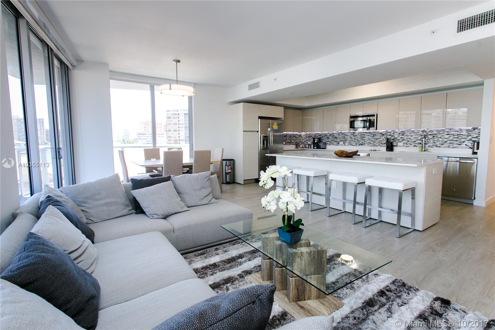 An open-plan living room and kitchen feature light wood floors, modern cabinetry, and balcony views — 2600 E Hallandale Beach Blvd, Hallandale Beach FL 33009, HALLANDALE BEACH, FL