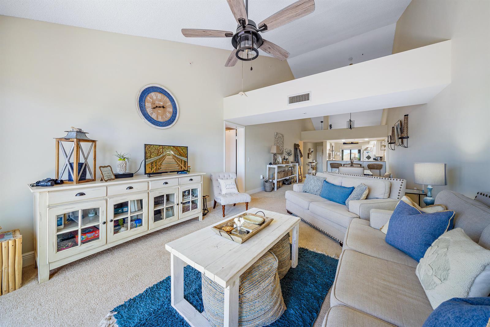 A living room features a white media console, two sofas, a coffee table, and a ceiling fan — 1701 Marina Isle Way # 504, Jupiter FL 33477, JUPITER, FL
