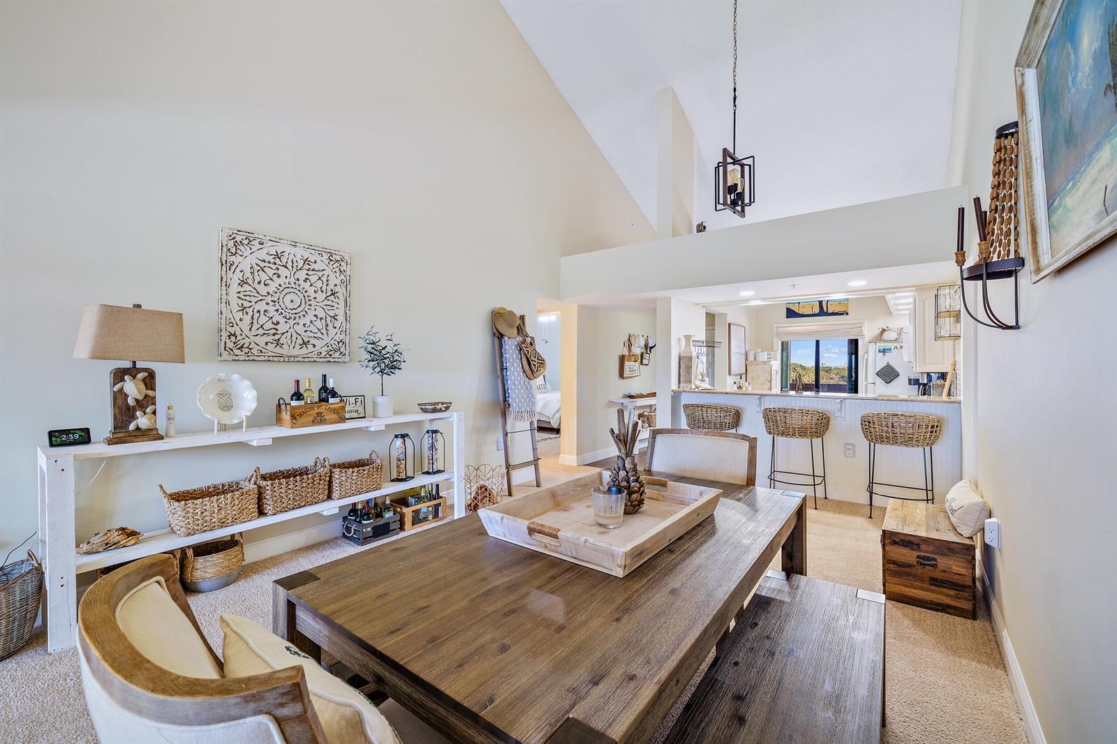 A dining area with a wooden table and bench sits before an open kitchen with barstools — 1701 Marina Isle Way # 504, Jupiter FL 33477, JUPITER, FL