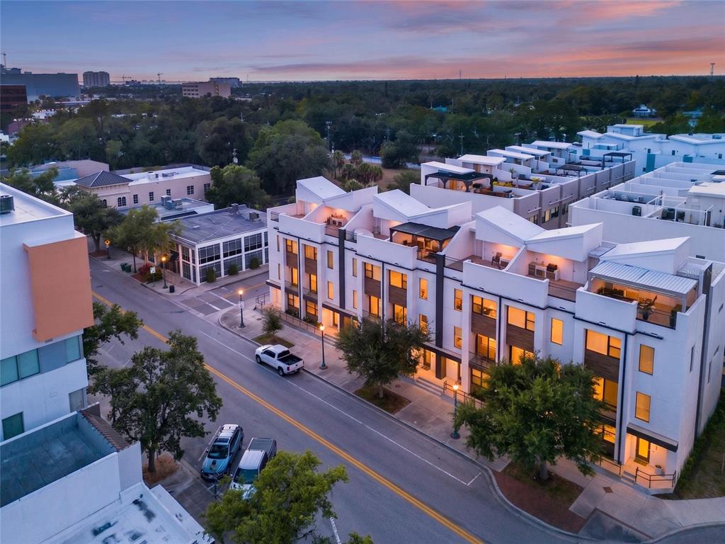 An aerial view shows a row of modern white townhomes with rooftop terraces along a street — 2187 MAIN STREET, SARASOTA, FL
