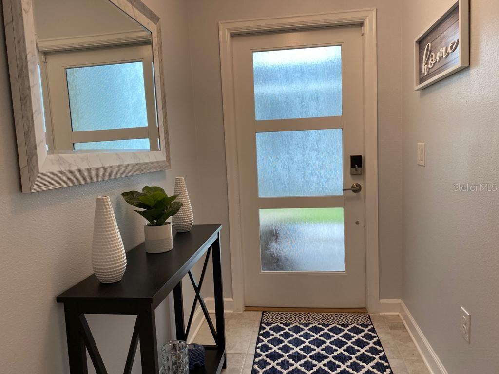 An entryway features a console table, a mirror, a front door with glass panels, and decor — 637 OCEAN COURSE AVENUE, DAVENPORT, FL