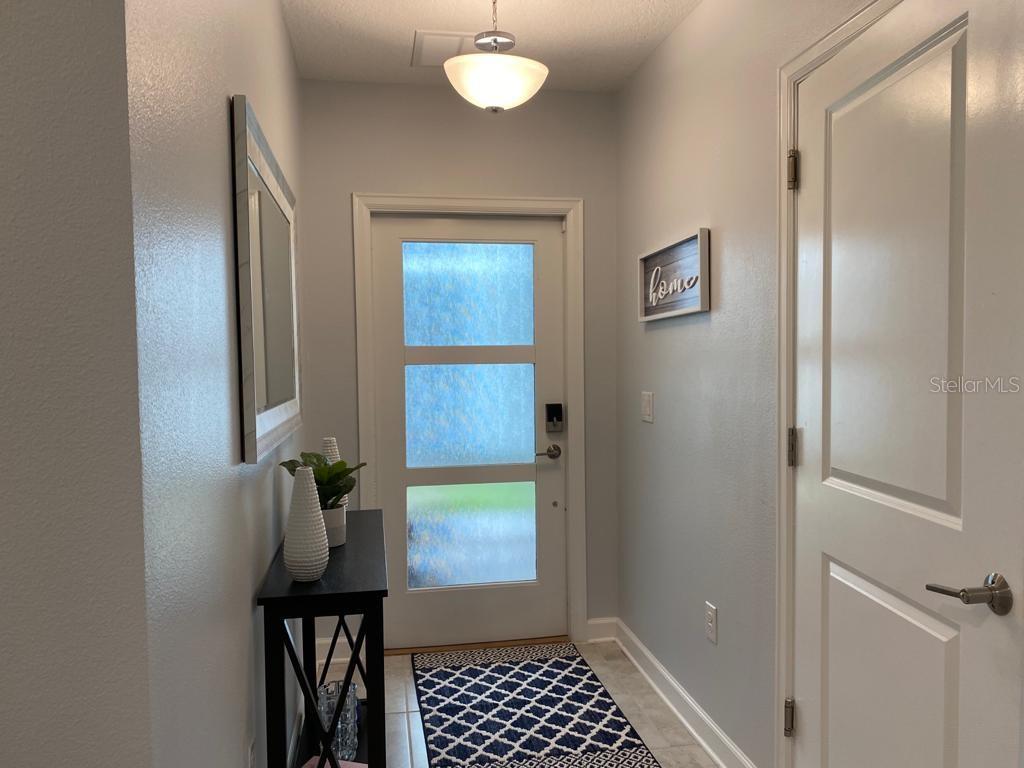 A bright entryway features a white front door with frosted glass panels and a console table — 637 OCEAN COURSE AVENUE, DAVENPORT, FL
