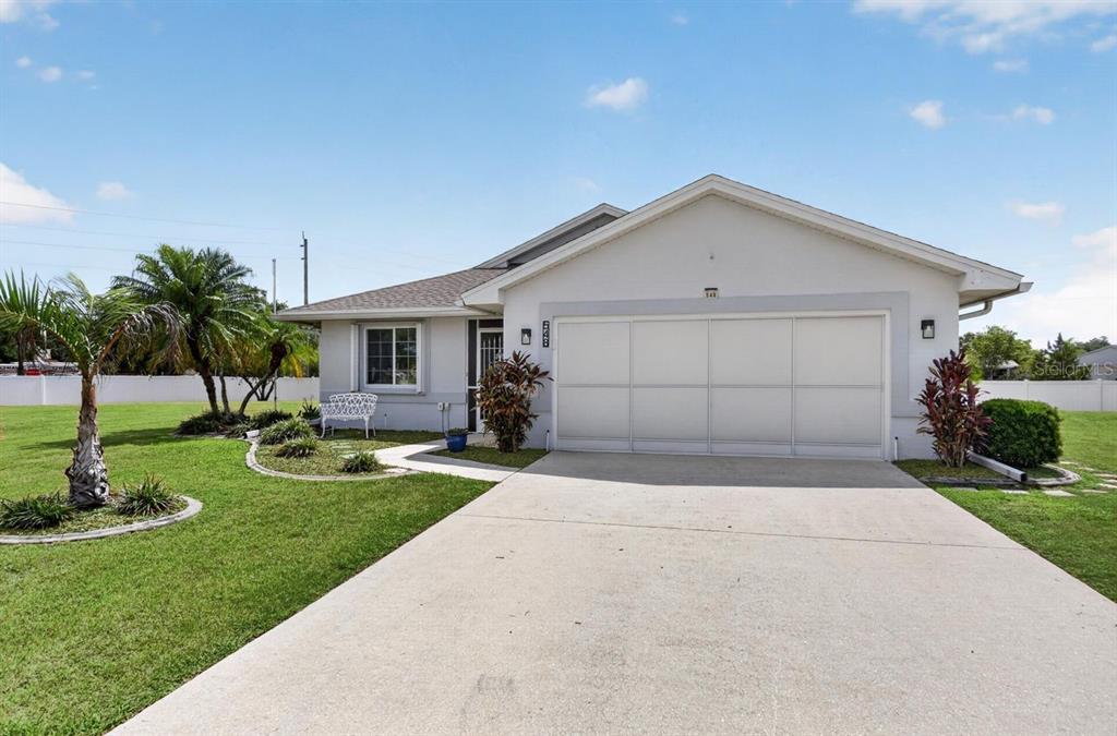 A single-story house with a white garage door, concrete driveway, and palm trees in front — 548 ROSE APPLE CIRCLE, PORT CHARLOTTE, FL