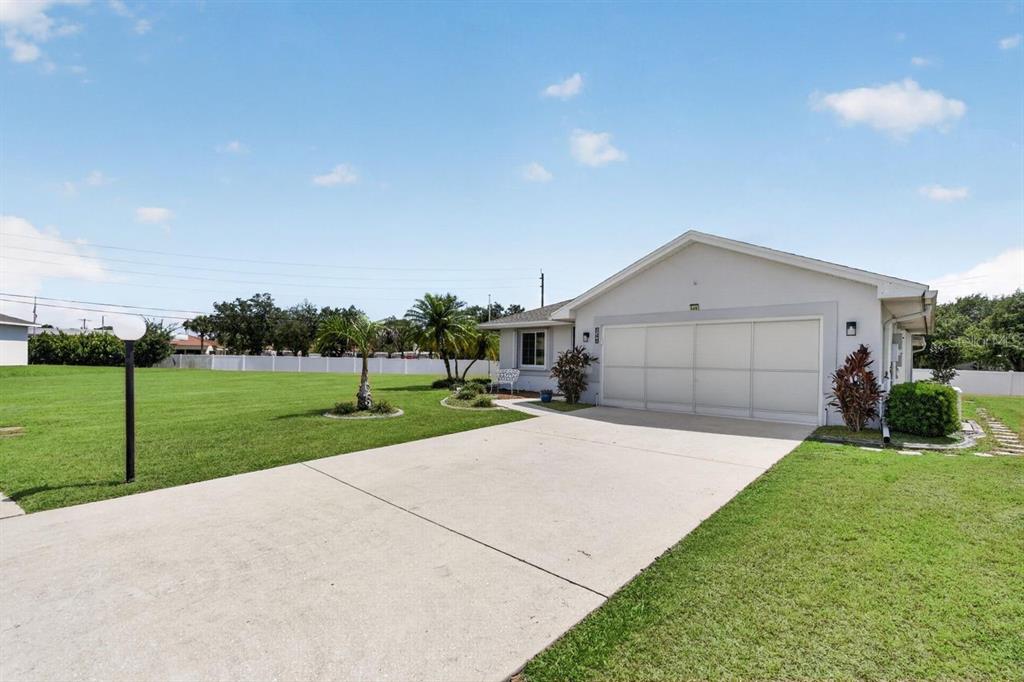 A single-story house with a white garage door and a large front lawn — 548 ROSE APPLE CIRCLE, PORT CHARLOTTE, FL
