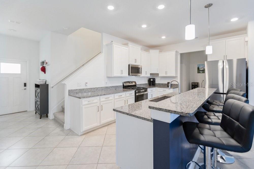 A kitchen with white cabinets, granite countertops, and a central island with a sink — 8241 CORNER PINE WAY, NEW PORT RICHEY, FL