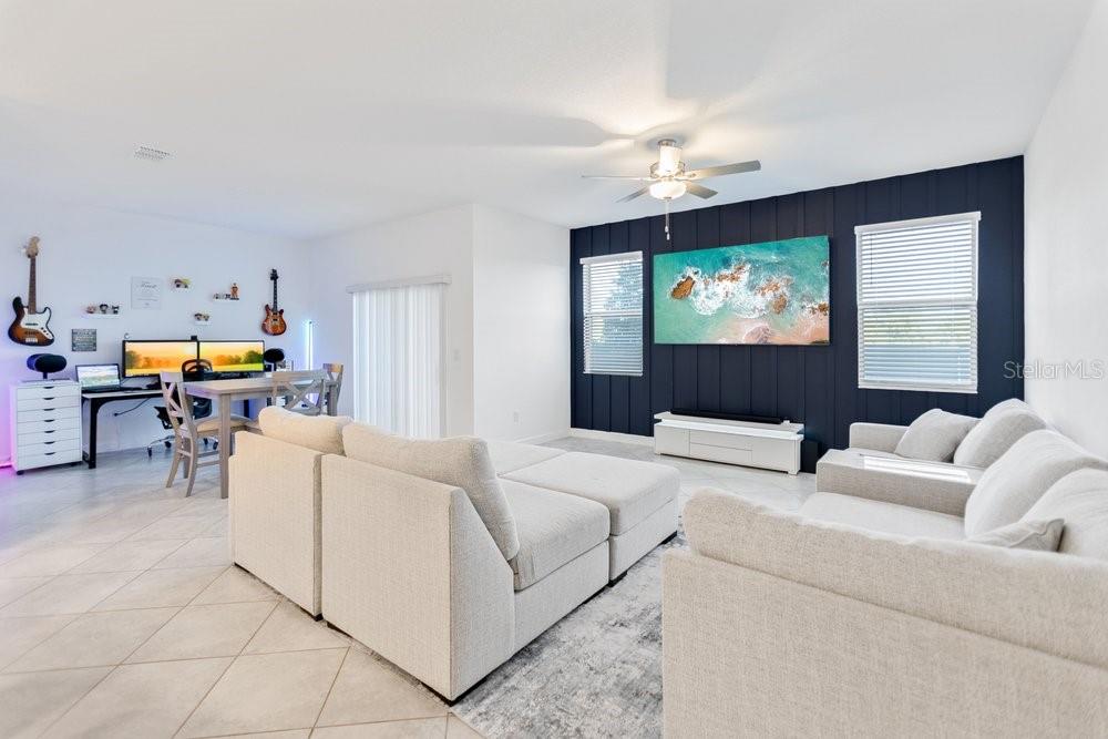 A kitchen with white cabinets and granite countertops sits next to a carpeted staircase — 8241 CORNER PINE WAY, NEW PORT RICHEY, FL