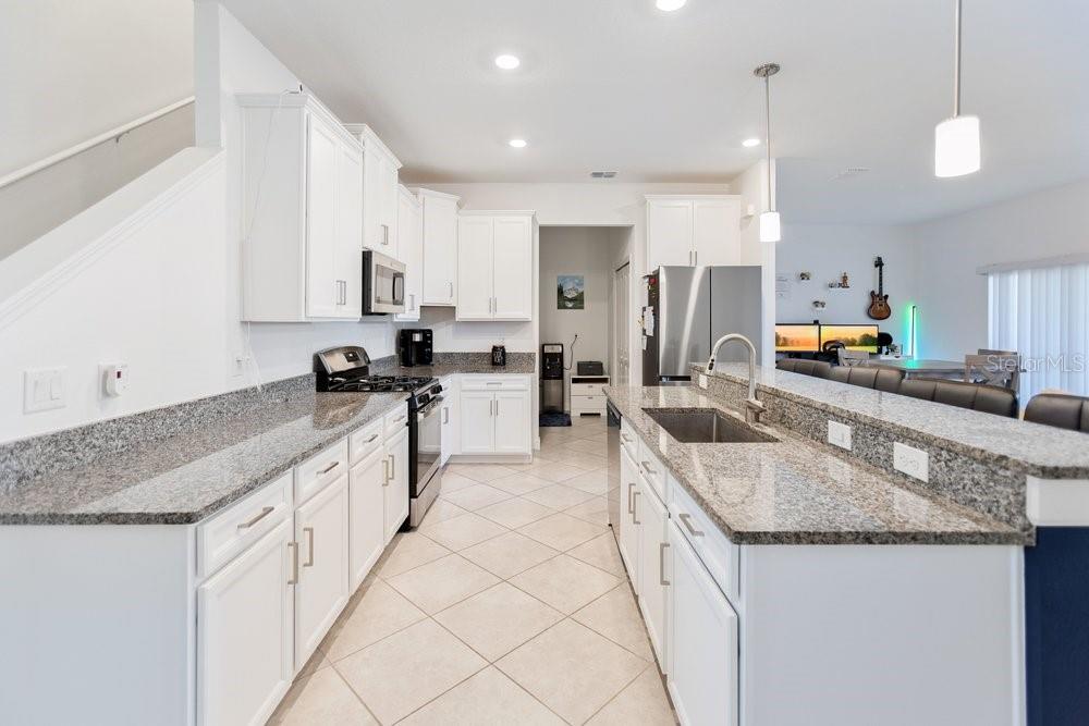 A kitchen with white cabinets, granite countertops, a breakfast bar, and stainless steel appliances — 8241 CORNER PINE WAY, NEW PORT RICHEY, FL