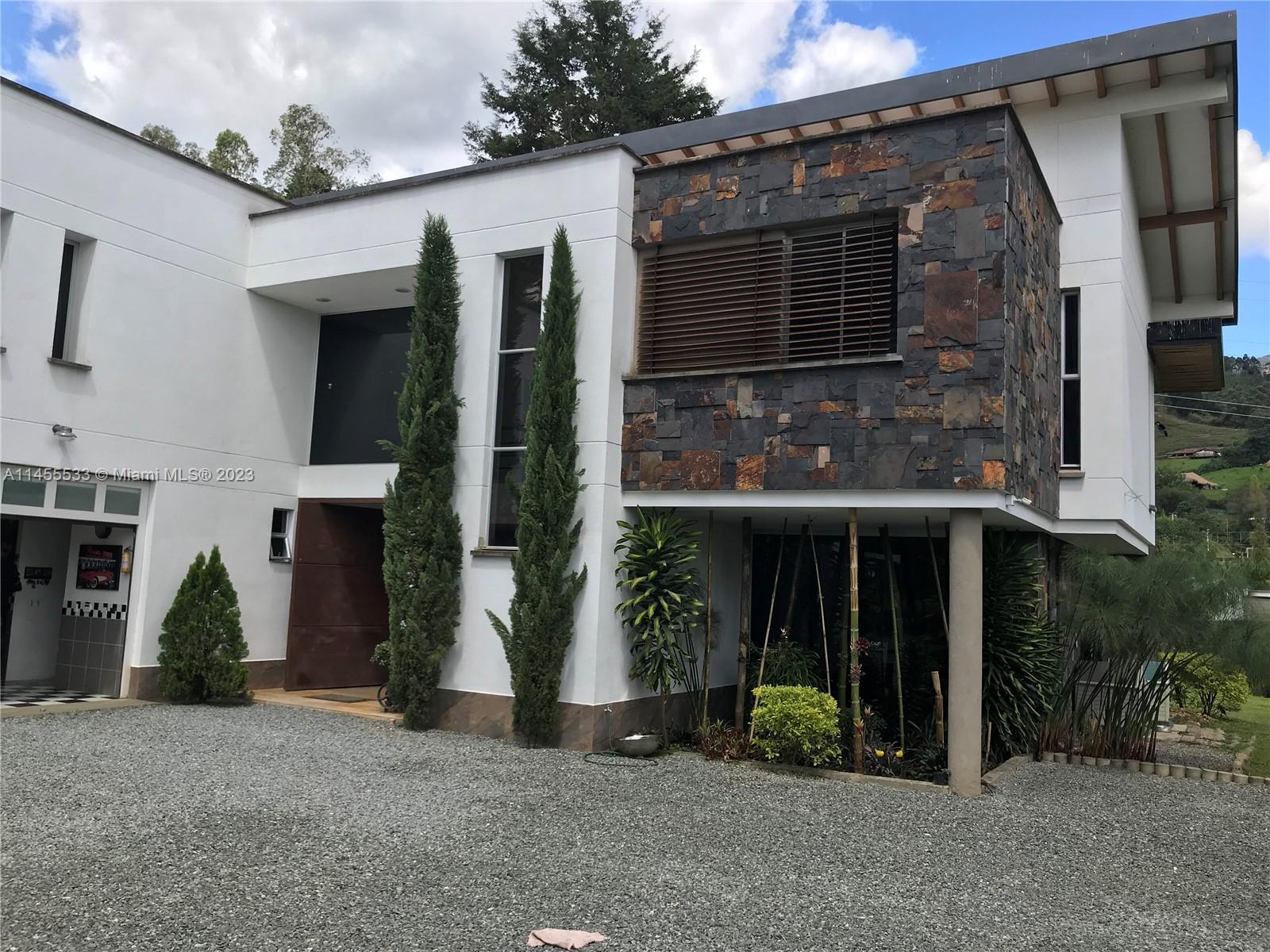 A modern two-story house features white walls, stone cladding, and a gravel driveway — CRA 24 - 36DSUR151 S EL Escobero, AN 055421, AN