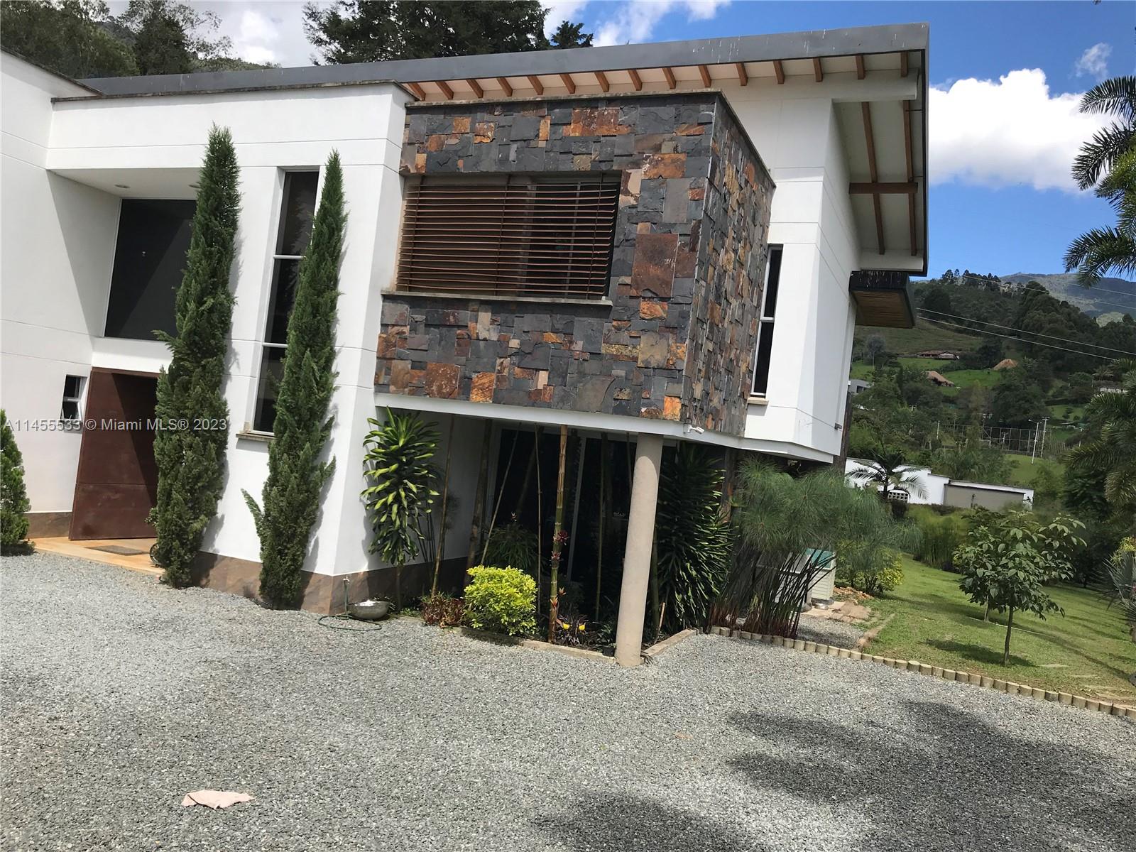 A modern two-story house features a stone-clad upper level and a gravel driveway — CRA 24 - 36DSUR151 S EL Escobero, AN 055421, AN