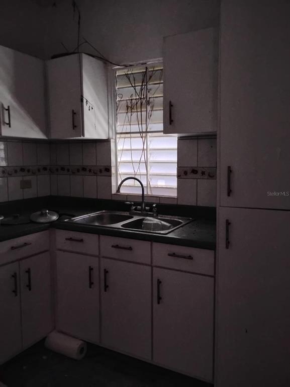 A dimly lit kitchen features white cabinets, a double-basin sink, and a window with blinds — 344 CARR NUEVA BO JAGUITAS, HORMIGUEROS, PR