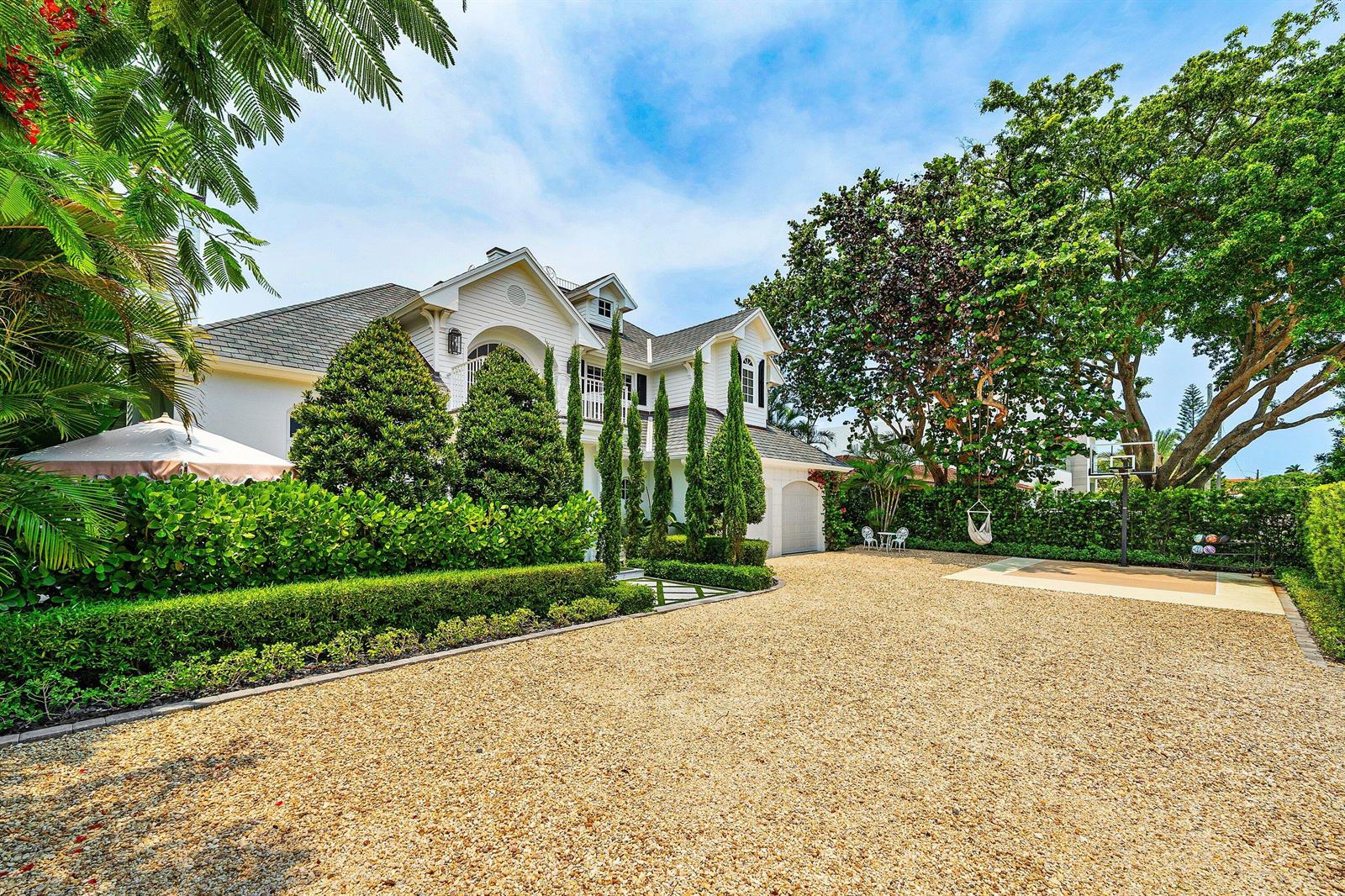 A large white house with a gravel driveway, manicured hedges, and a basketball hoop — 477 NE Spanish Court, Boca Raton FL 33432, BOCA RATON, FL