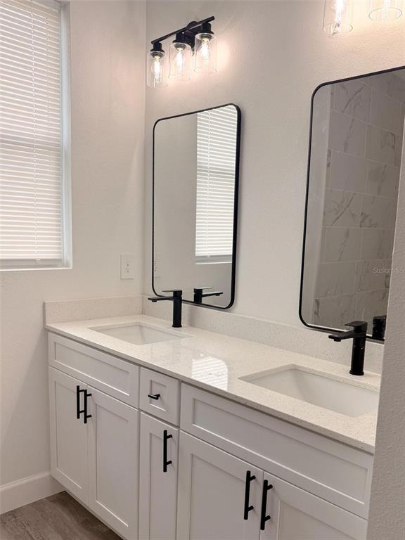 A modern bathroom features a double vanity with white cabinets, black hardware, and two mirrors — 824 HANOVER AVENUE, SEBRING, FL