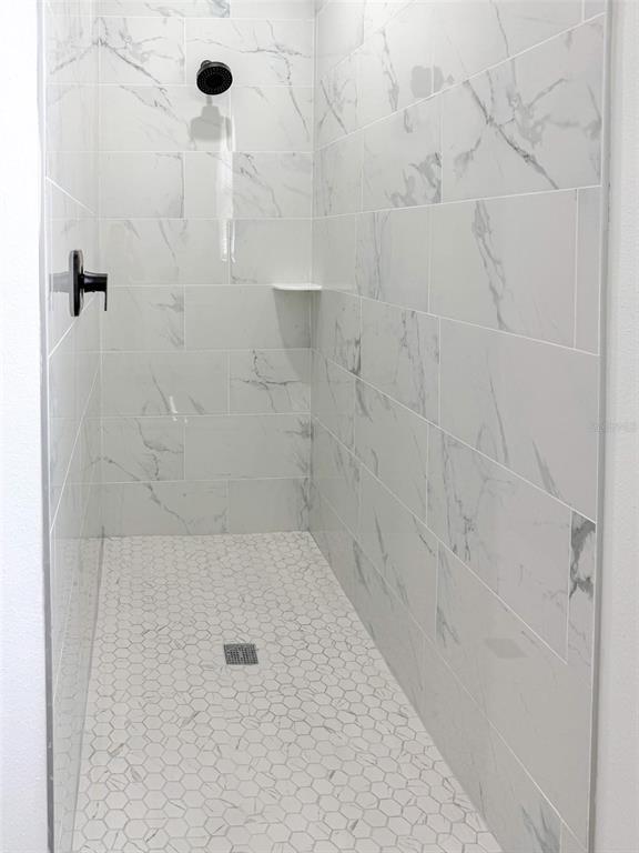 A walk-in shower features white marble-look wall tiles, a hexagonal tile floor, and black fixtures — 824 HANOVER AVENUE, SEBRING, FL