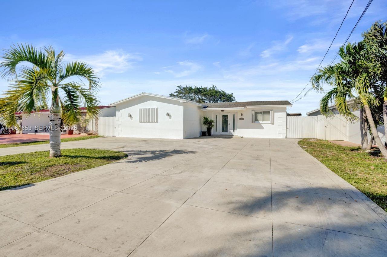 A white single-story house with a large concrete driveway and palm trees in the front — 6617 Dahlia Dr, Miramar FL 33023, MIRAMAR, FL