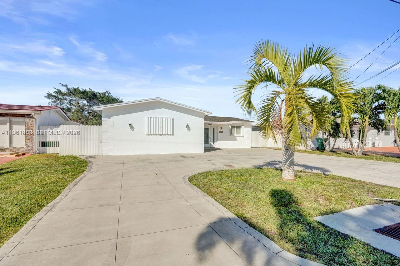 A white single-story house features a large concrete driveway and a prominent palm tree — 6617 Dahlia Dr, Miramar FL 33023, MIRAMAR, FL