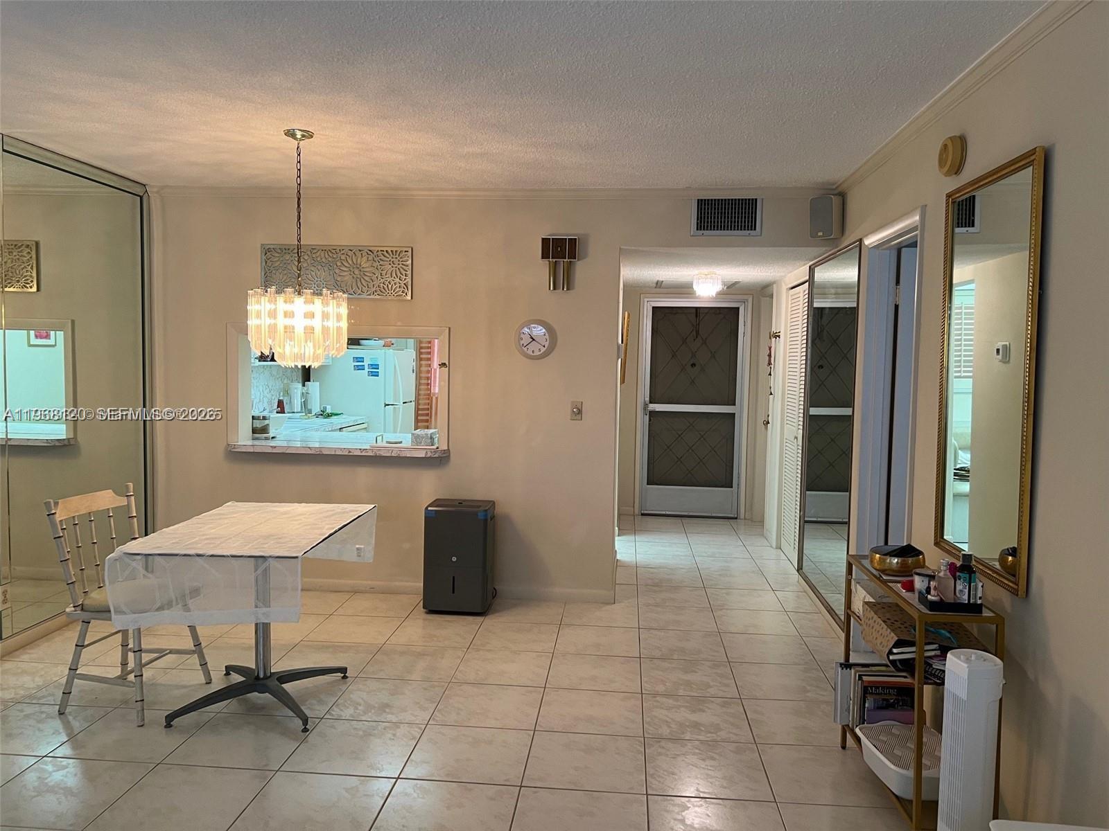 A dining area features tile flooring, a chandelier, a pass-through window, and mirrored wall panels — 215 SE 3rd Ave # D, Hallandale Beach FL 33009, HALLANDALE BEACH, FL