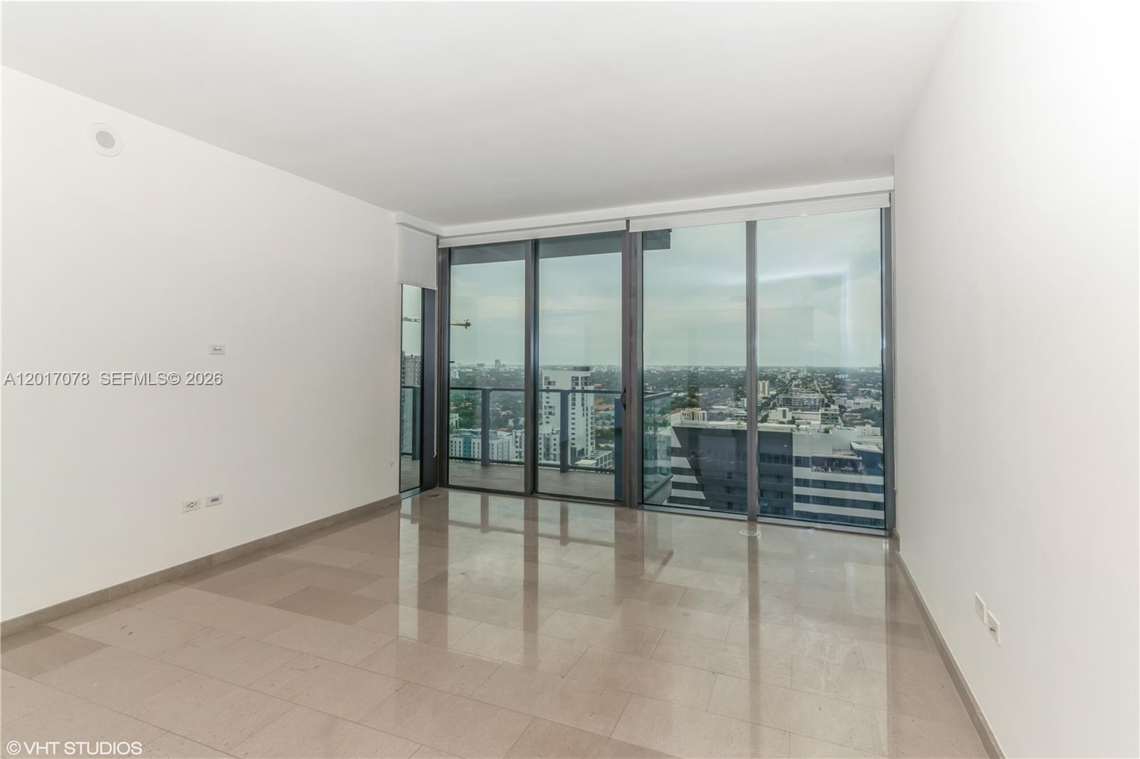 An empty room with light-colored tile floors and floor-to-ceiling windows overlooking a city skyline — 88 SW 7th St # 2508, Miami FL 33130, MIAMI, FL