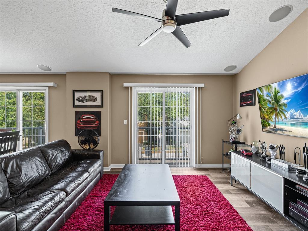 A living room features a black leather sofa, a magenta rug, and a wall-mounted television — 6774 BREEZY PALM DRIVE, RIVERVIEW, FL