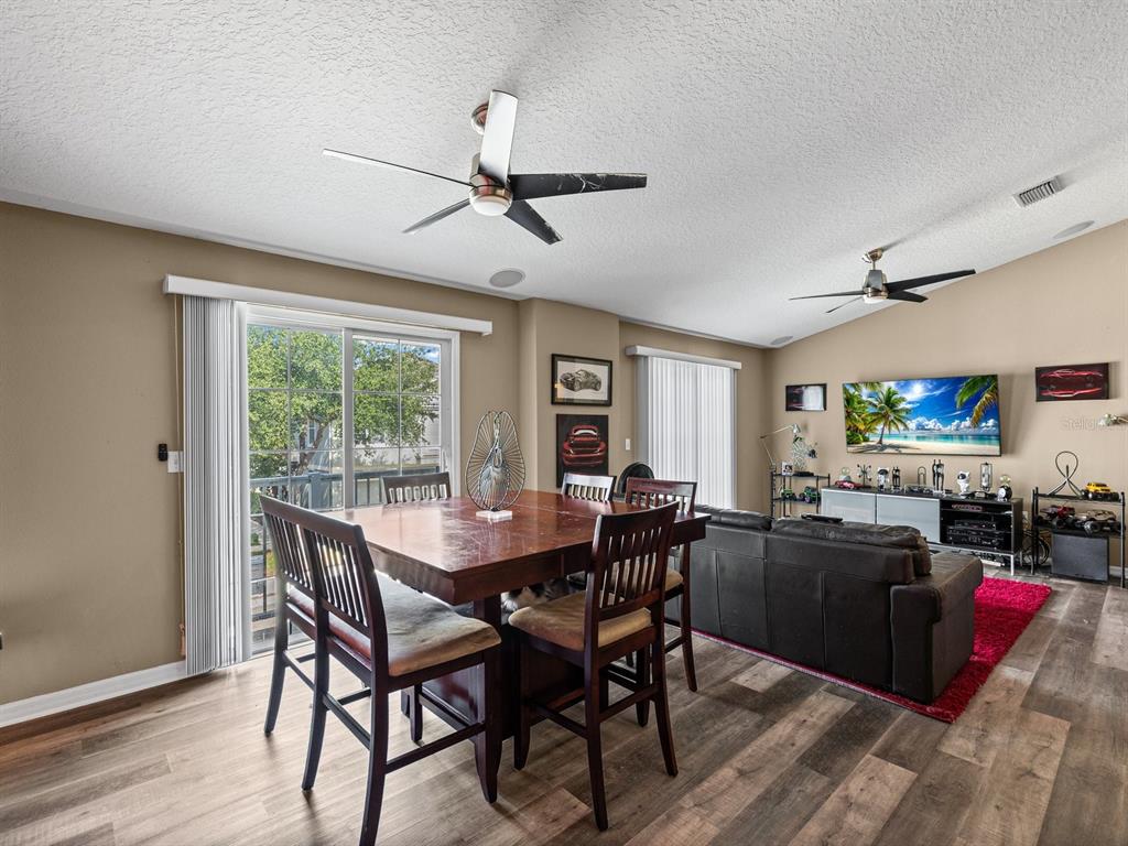 A dining area with a wooden table and chairs sits adjacent to a living room — 6774 BREEZY PALM DRIVE, RIVERVIEW, FL