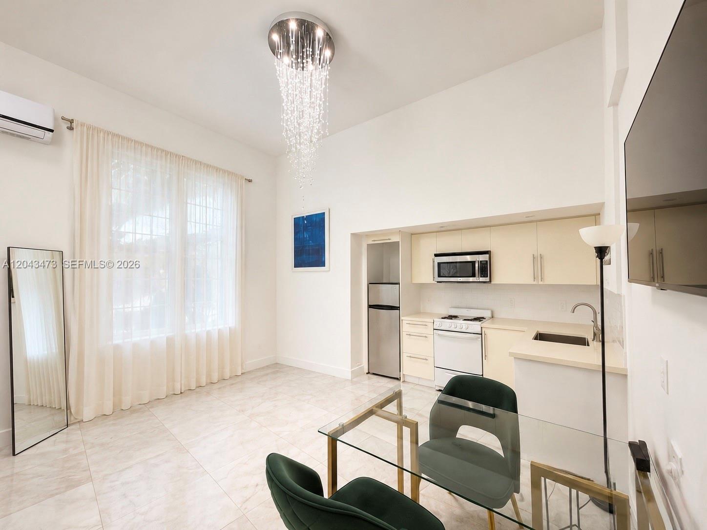 A kitchen and dining area features a crystal chandelier, white cabinets, and green chairs — 3025 Indian Creek Dr # 109, Miami Beach FL 33140, MIAMI BEACH, FL